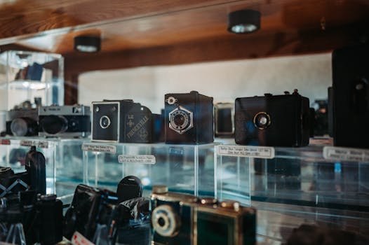 A collection of vintage cameras displayed in glass case showcases historic photographic technology.