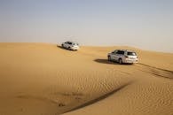 四轮驱动车辆在阿布扎比的沙丘间穿行，展现了沙漠冒险与探索的乐趣