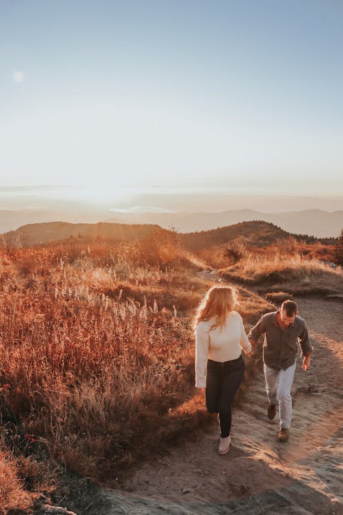 Woman Holding the Hand of a Man While Hiking