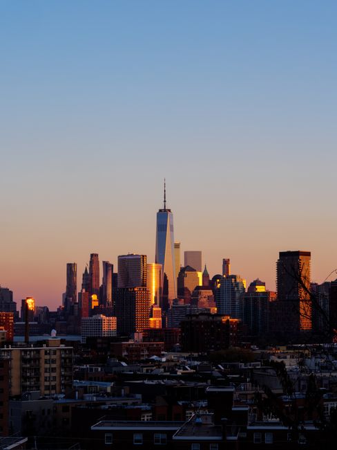 Fotomural Impresionante vista del horizonte de Jersey City al atardecer, con rascacielos bañados en la cálida luz del sol.