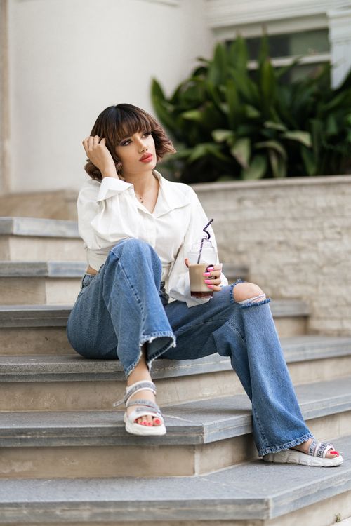 Free Trendy woman relaxing with coffee on city steps in Urmia, Iran. Stylish and casual fashion scene. Stock Photo