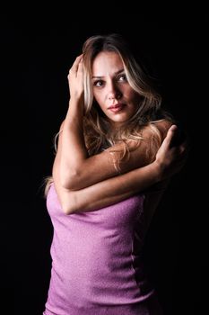 Portrait of a woman in a pink dress with arms crossed in a studio setting.