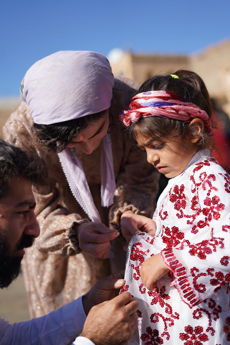 Mother And Father Helping Daughter With Clothes