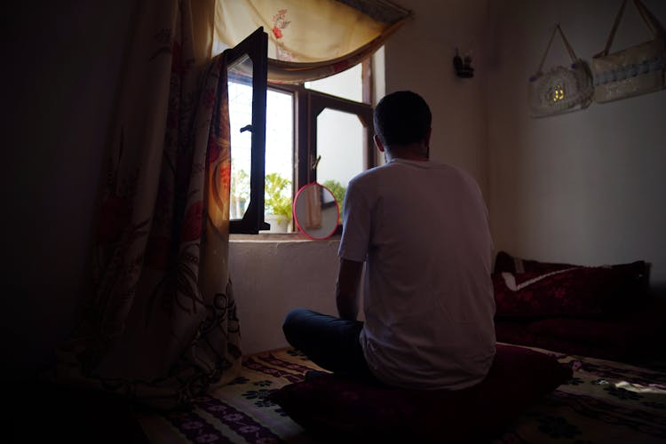 Back Of A Man Sitting On A Pillow On The Bed