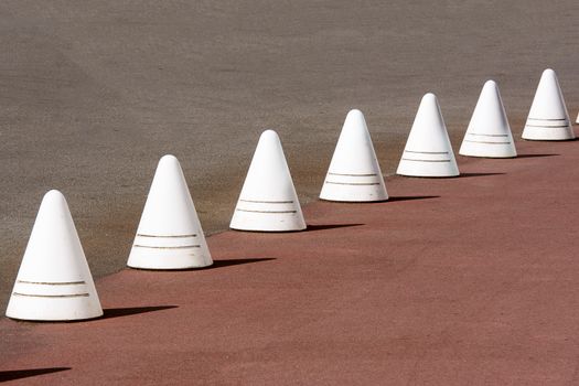 White traffic cones lined up in a repeating row on a road.