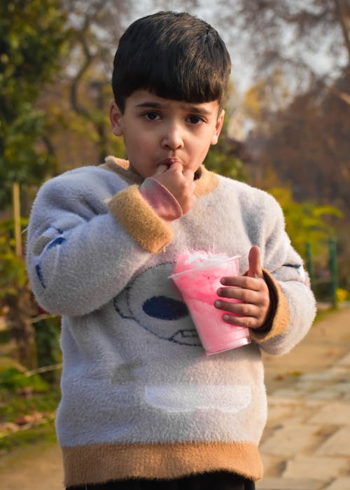 Boy Wearing Sweater Eating Cotton Candy