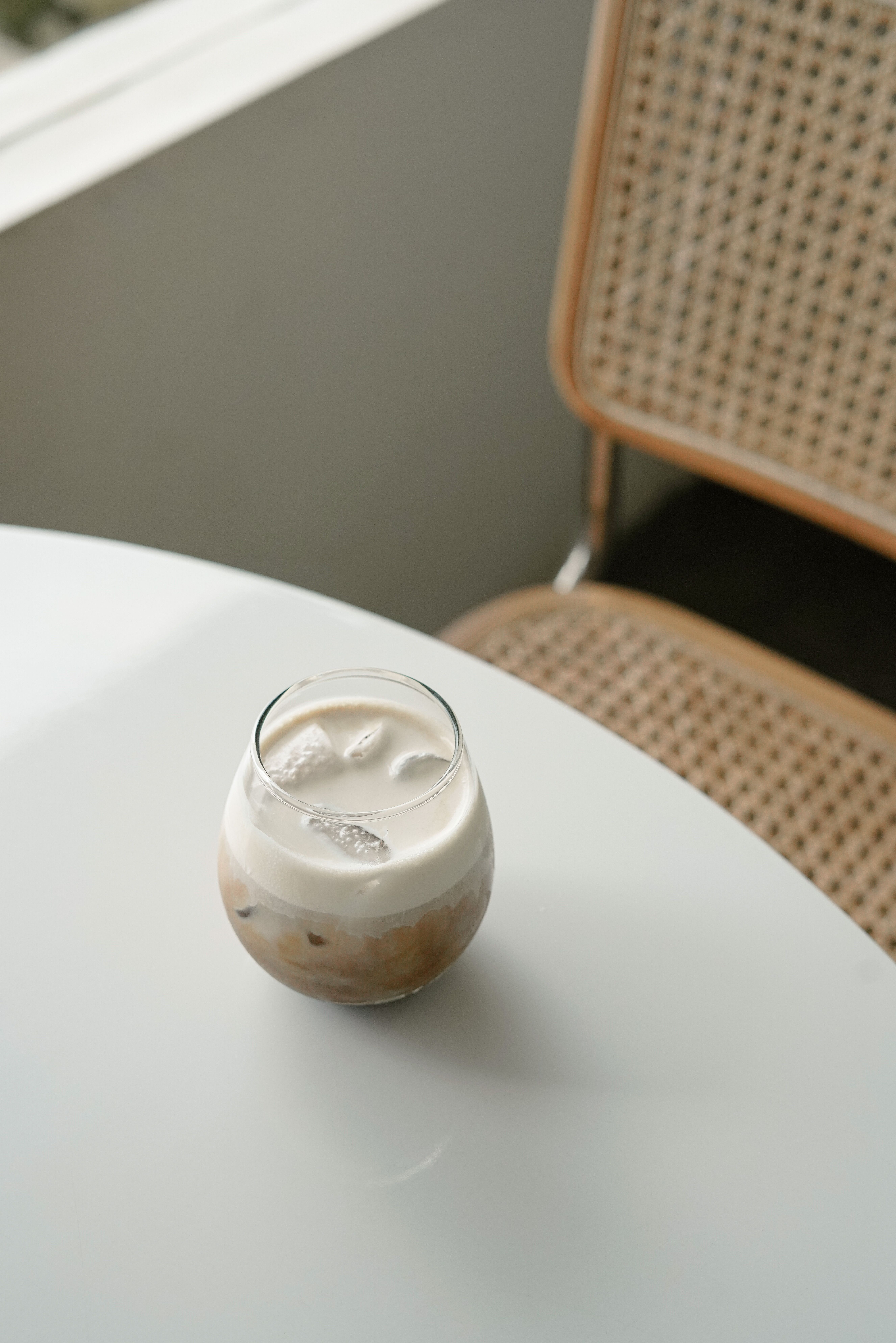 A refreshing iced coffee sits on a sleek white table indoors, offering a minimalist aesthetic.