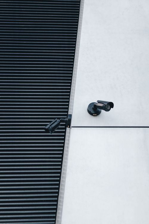 Free A close-up of modern surveillance cameras mounted on a sleek industrial building exterior for security. Stock Photo