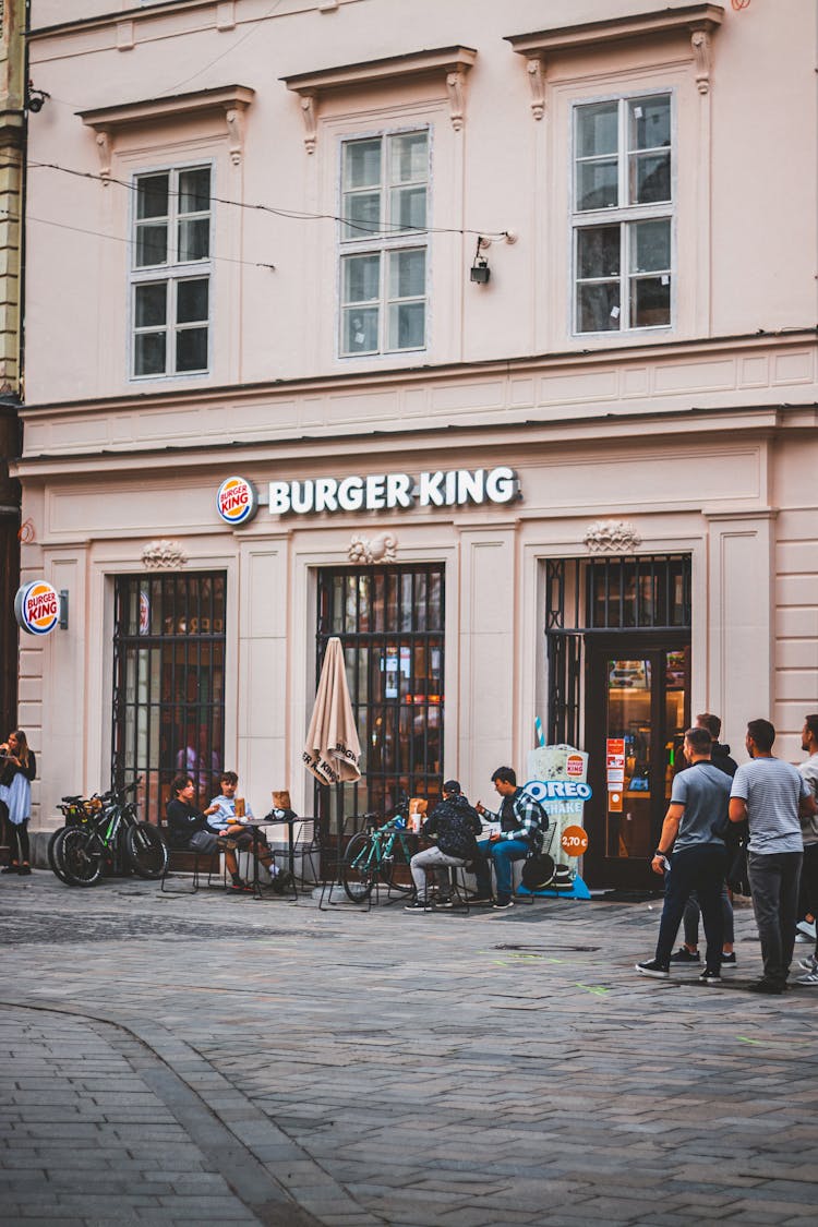 People Sitting By Outdoor Tables Of Burger King Restaurant