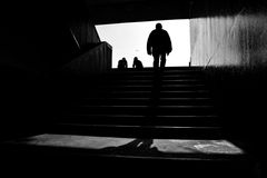 A striking black and white silhouette of a person walking upstairs, creating a moody atmosphere.