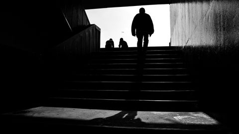 A striking black and white silhouette of a person walking upstairs, creating a moody atmosphere.