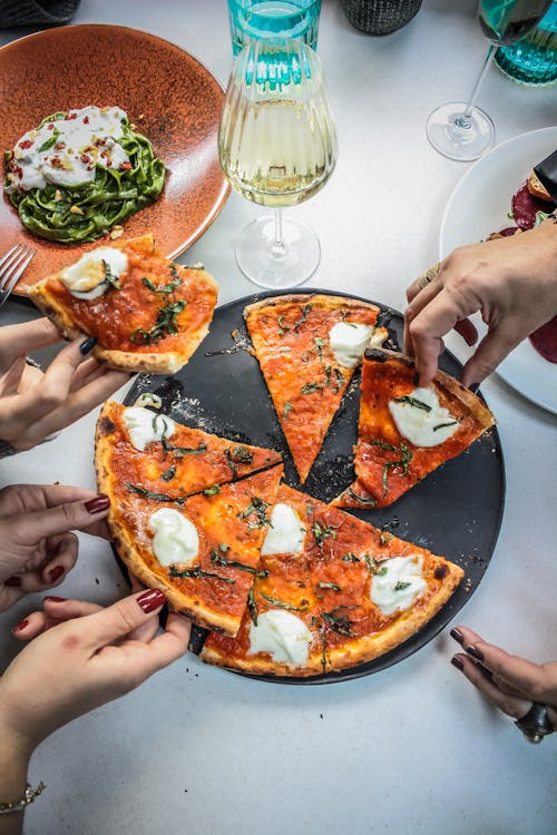 Hands Holding Slices of Pizza 