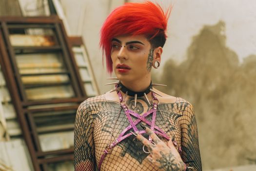 A striking portrait of a tattooed model with vibrant red hair and punk style in an urban setting.