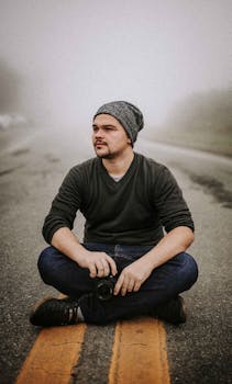 在巴西巴拉那皮亚卡巴，一名男子头戴无檐帽，盘腿坐在雾气弥漫的道路上