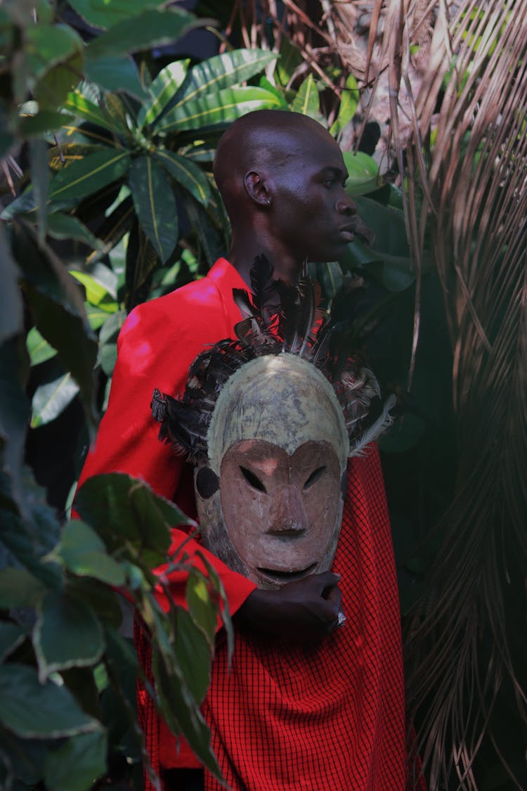 A Man In Red Shirt Holding A Wooden Dogon Mask