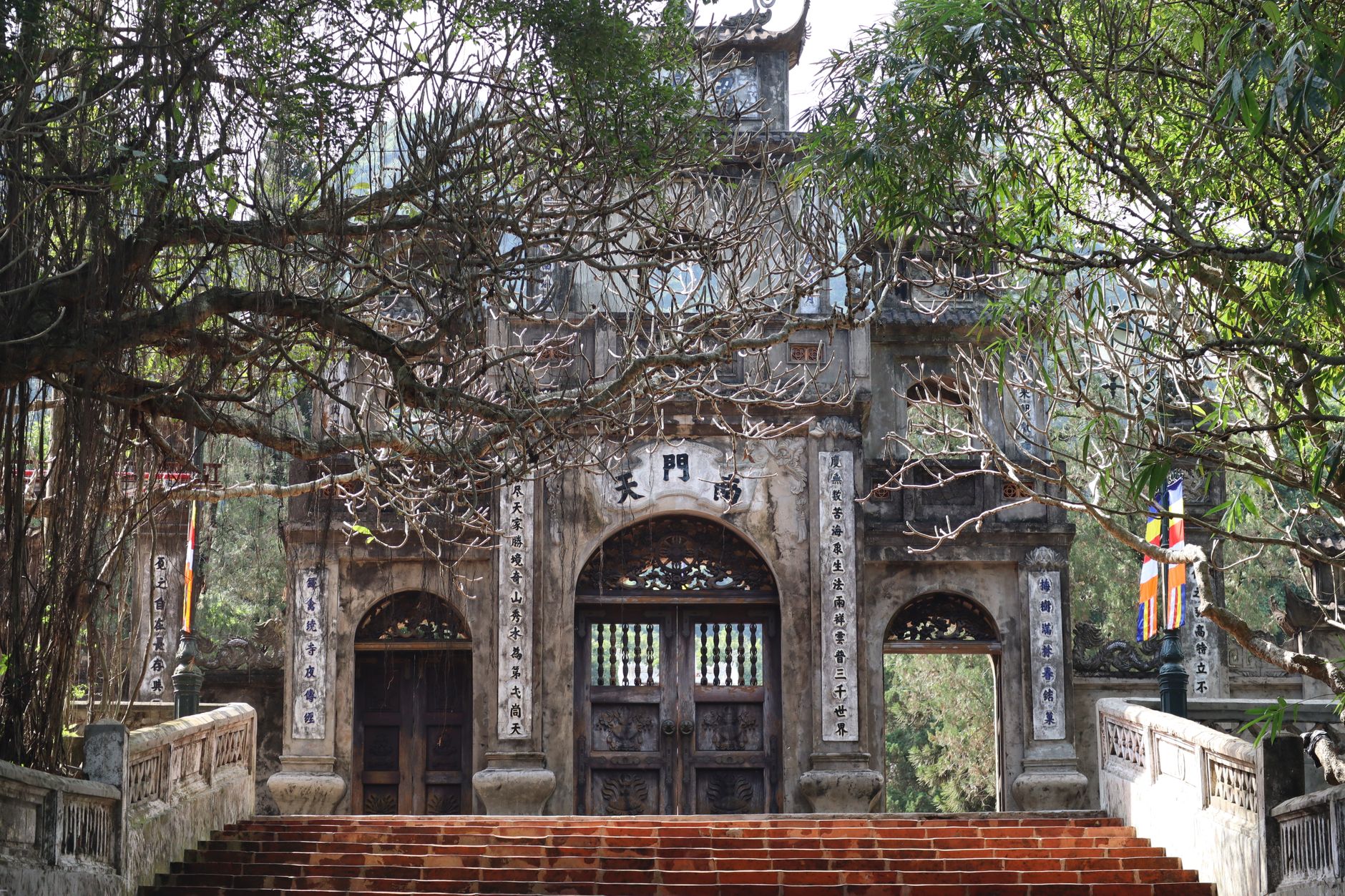 A majestic stone temple entrance surrounded by lush trees, showcasing intricate architectural details. Perfect for cultu