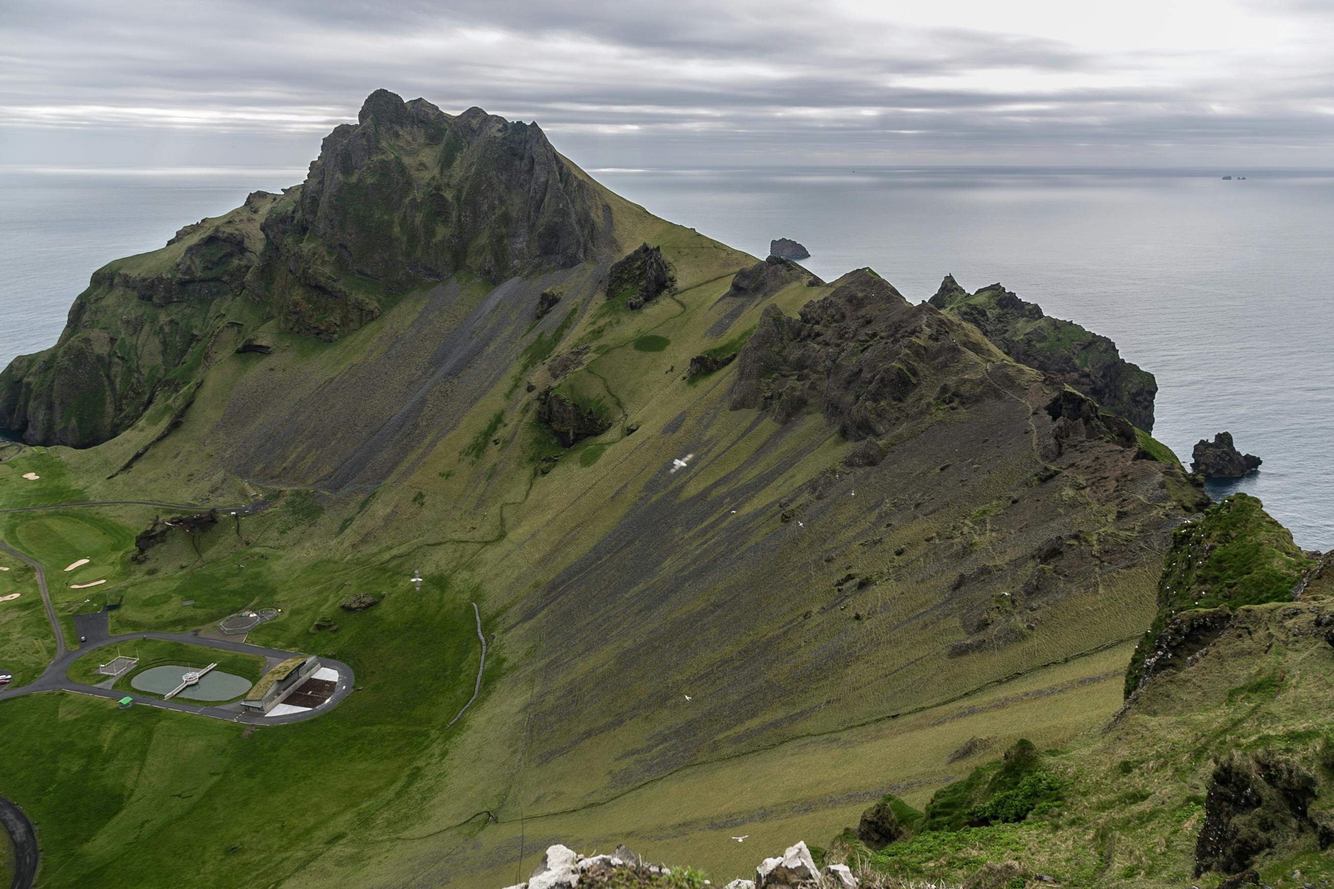 多云天空下，俯瞰冰岛沿海山脉与海洋的鸟瞰图令人惊叹