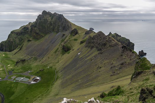多云天空下，俯瞰冰岛沿海山脉与海洋的鸟瞰图令人惊叹