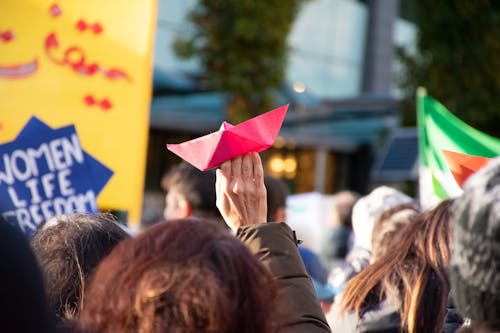 Free Woman Holding Paper Ship among Protesting Crowd Stock Photo