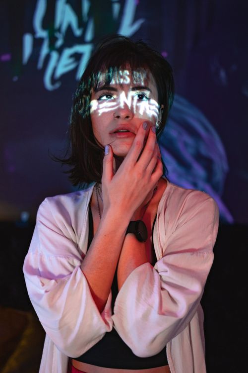 Free Artistic portrait of a woman with projected text and light effects on her face, indoors at night. Stock Photo