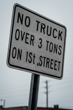 Urban traffic sign indicating a weight limit for trucks on 1st Street.