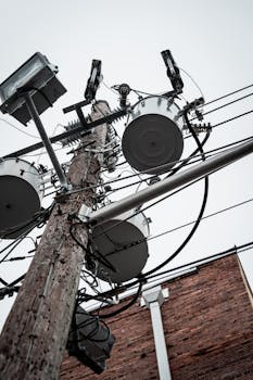 Close-up view of an urban utility pole with high voltage wires and transformers.