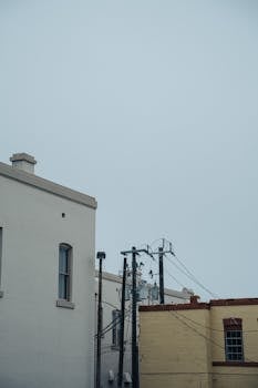 Overcast urban scene featuring architecture and power lines, conveying a moody atmosphere.