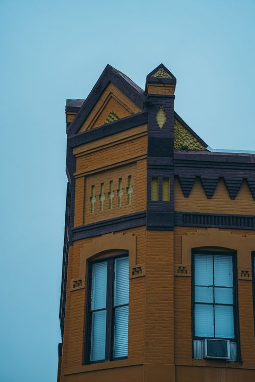 Free A vibrant orange brick building with gothic architectural features against a clear sky. Stock Photo