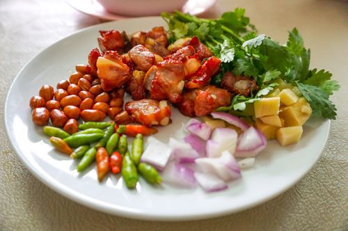 Free Vibrant Asian appetizer on a plate featuring fresh vegetables, nuts, and marinated meat. Stock Photo