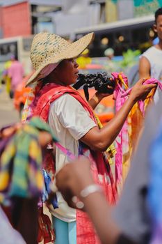 Colorful street market in Abidjan showcasing local fashion with a woman in a wide-brim hat.