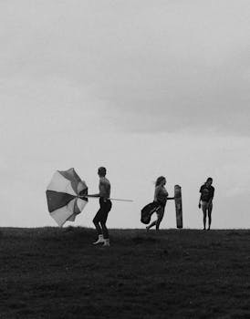 Three people playing with an umbrella in a grassy field, Edmonton.