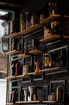 A collection of modern coffee makers and mugs displayed on stylish shelves, ideal for cafes or coffee enthusiasts.