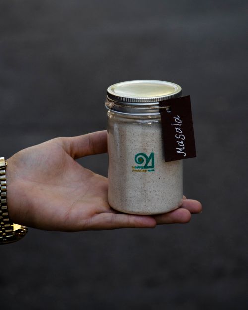 Free Close-up of a hand holding a jar labeled 'Masala', showcasing spices against a dark background. Stock Photo
