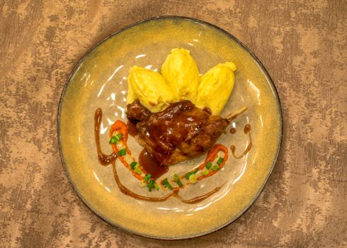 Top view of roast meat with mashed potatoes and decorative sauce on a plate.