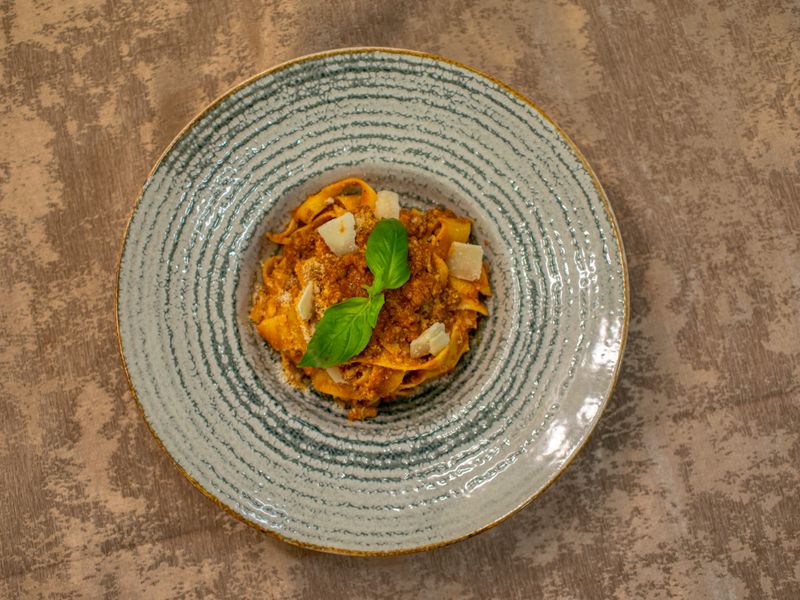 Delicious pasta served with cheese, sauce, and basil, perfectly plated for a culinary deli