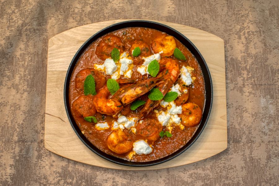 Delicious shrimp curry garnished with fresh mint leaves, served on a wooden cutting board.