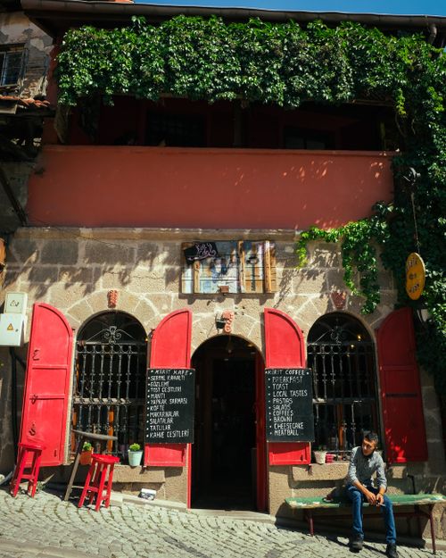 Free Charming café in Ankara, Türkiye with vibrant red shutters and cobblestone street views. Stock Photo
