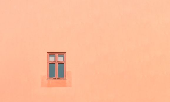 An orange wall with a single window in Oslo, showcasing minimalist architecture.
