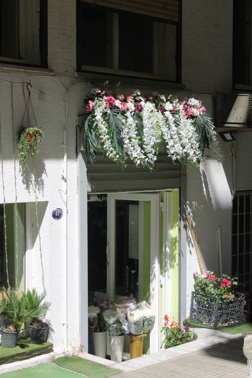 Free Bright and inviting flower shop entrance adorned with lush floral arrangements in an urban setting. Stock Photo
