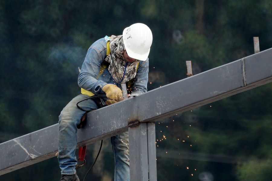 Worker sitting on a steel beam welding