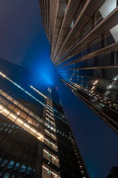 Low angle shot of futuristic skyscrapers with glass facades at night.