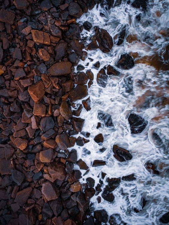Pebble Rocks Between View of Foamy Water between Pebbles · Free Stock Photo