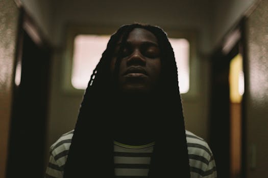 这幅肖像画风格黑暗而富有戏剧性，描绘了一名闭着眼睛、留着长辫子的男子