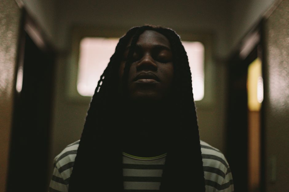 Dark and dramatic portrait of man with closed eyes and long dreadlocks.