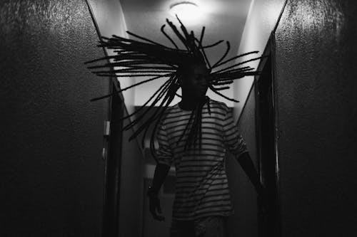 Grayscale Photography of Man Whipping His Dreadlocks Hair