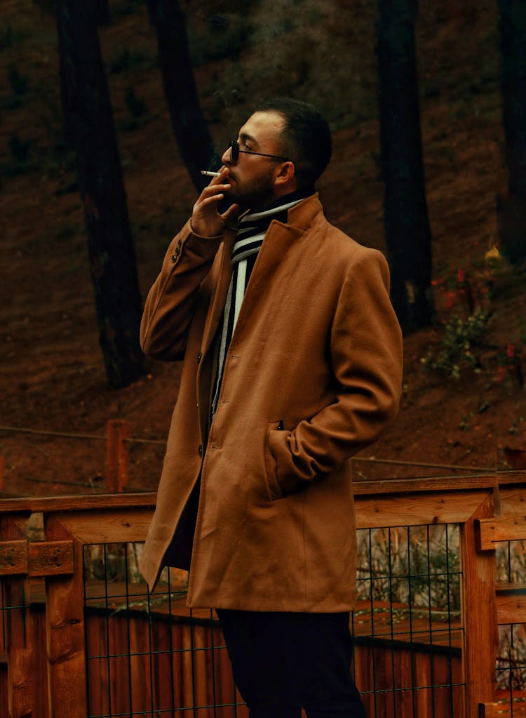 A Man In A Coat Smoking A Cigarette 