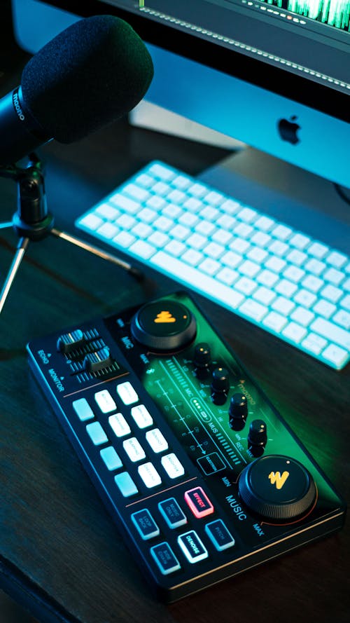 Lit up Mixing Console and Microphone on Desk