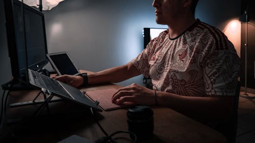 Free Man Sitting by a Desk and Working on a Laptop Stock Photo