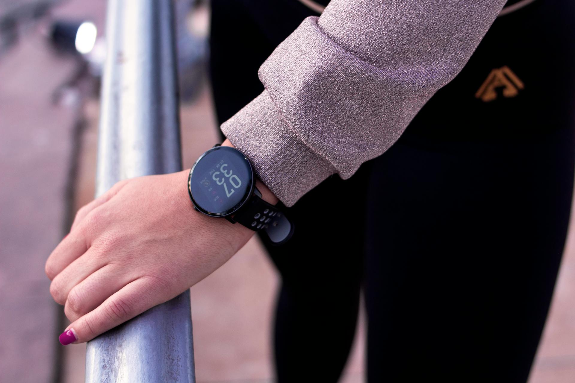 A close-up shot of a hand wearing a digital smartwatch, showcasing modern wearable technology outdoors.