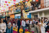 A vibrant street festival procession with a religious figure in Alto Lucero, Veracruz, Mexico, featuring colorful decorations and a large crowd.